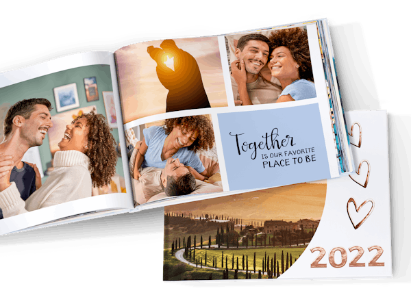 Álbum de fotos personalizado con fotos de 2022 abierto por la mitad con fotos de una pareja en sus vacaciones
