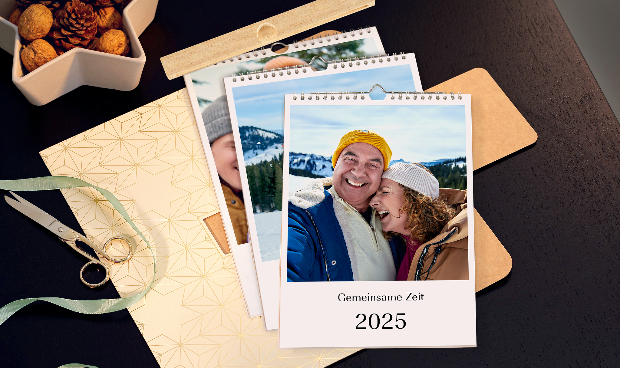 Geschenkverpackung für den Pixum Fotokalender mit mehreren gestapelten Kalendern auf einem Tisch