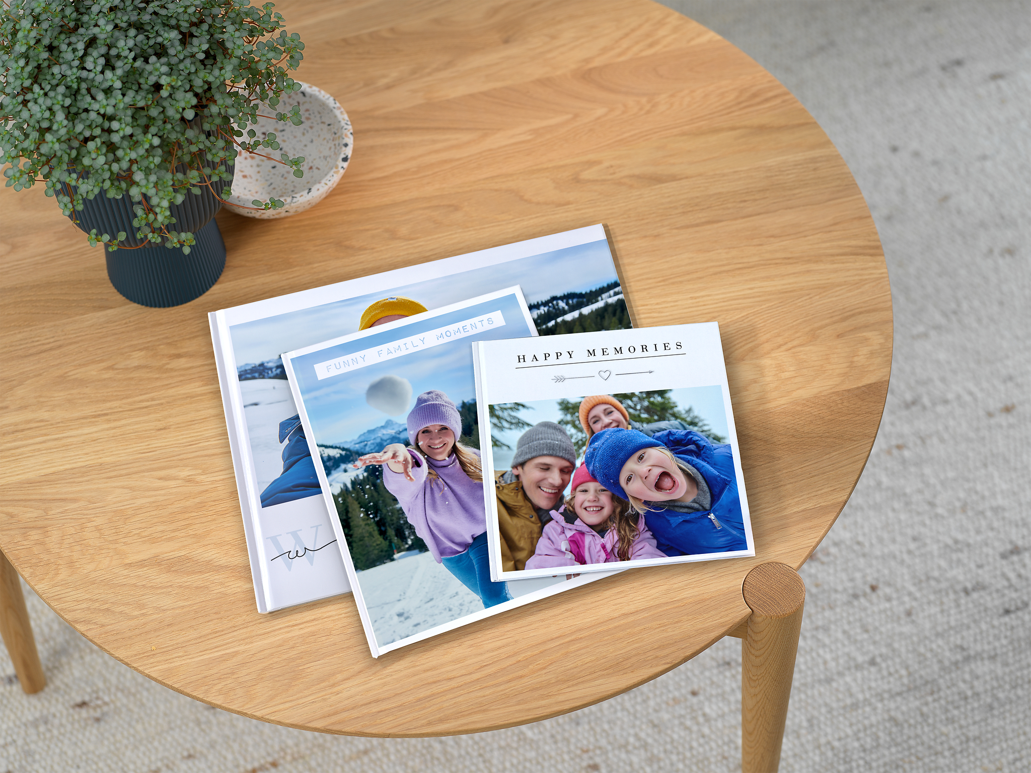 Pixum Fotobücher in drei verschiedenen Formaten mit Familienfotos im Schnee auf einem Tisch