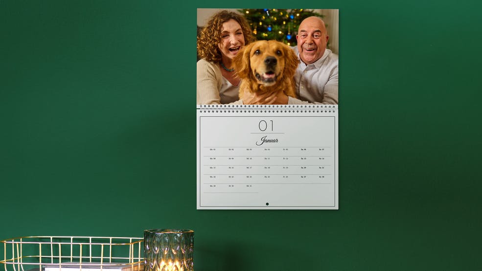 Pixum Fotokalender Klappkalender A4 mit einem Foto eines Pärchens mit Hund an einer grünen Wand