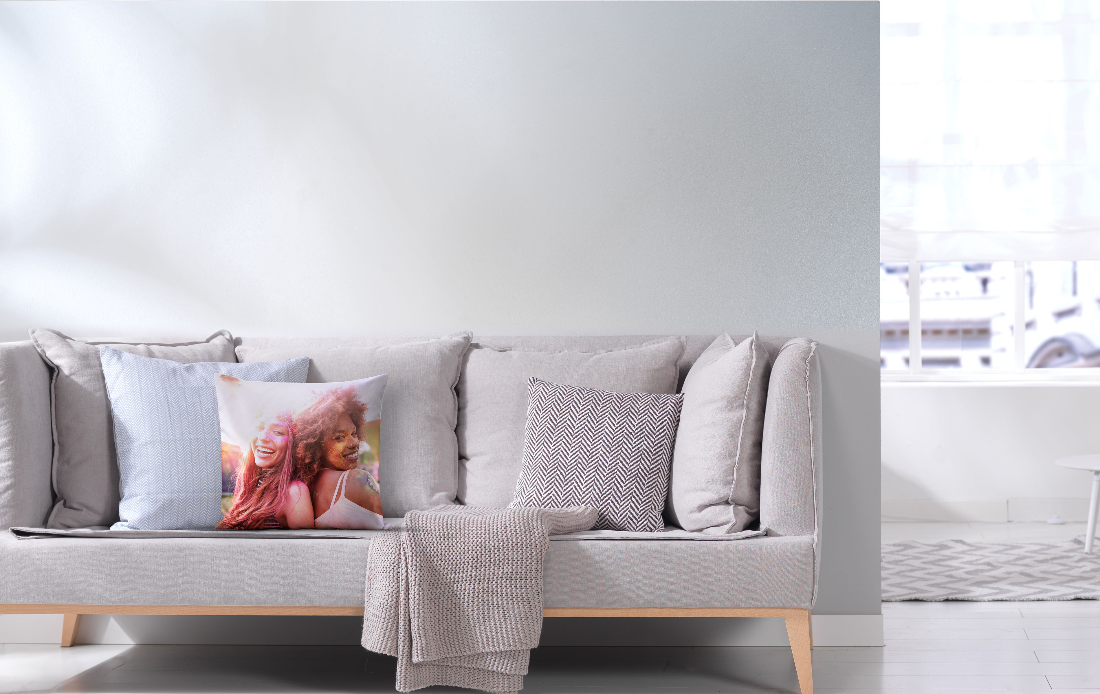 Foto-Kissenbezug 40x40 cm mit Freundemotiv auf einem Sofa.