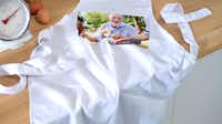 Foto-Kochschürze mit einem Foto von einem Großvater Foto-Kochschürze mit einem Foto von einem Großvater aufliegend auf einer Küchenzeile