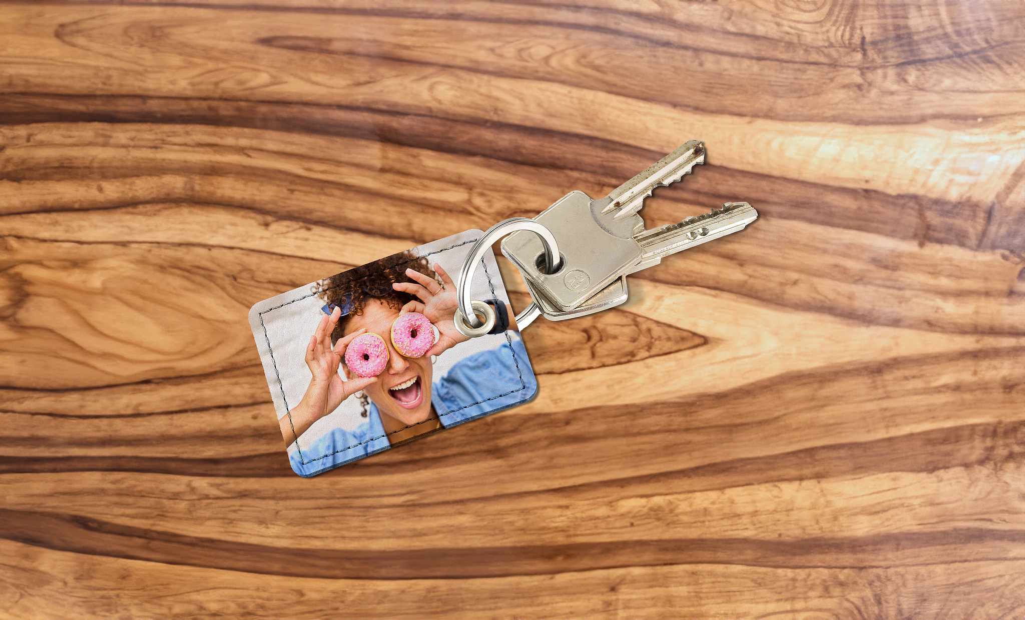 Rechthoekige sleutelhanger op een tafel. De foto op de sleutelhanger toont een vrouw.