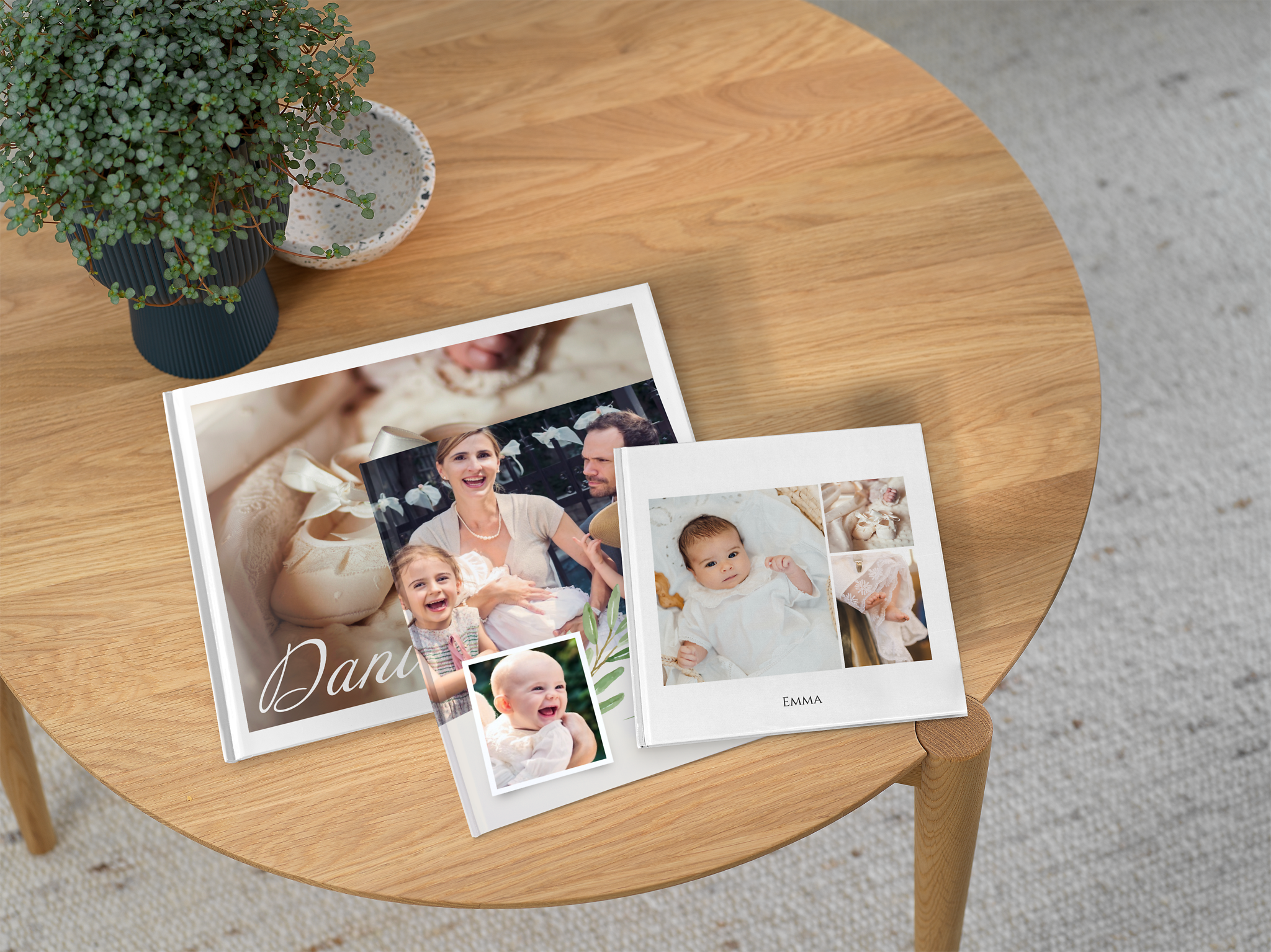 Tres álbumes de fotos de bautizo, con diferentes tamaños y unos puestos encima de otros sobre una mesa de madera