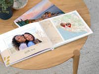 Fotobuch mit Landkarte & Reiseroute Ein aufgeklapptes Fotobuch zeigt ein Bild von Freundinnen gemeinsam auf einer Reise auf der linken und eine Landkarte ihrer Reiseroute auf der rechten Seite.