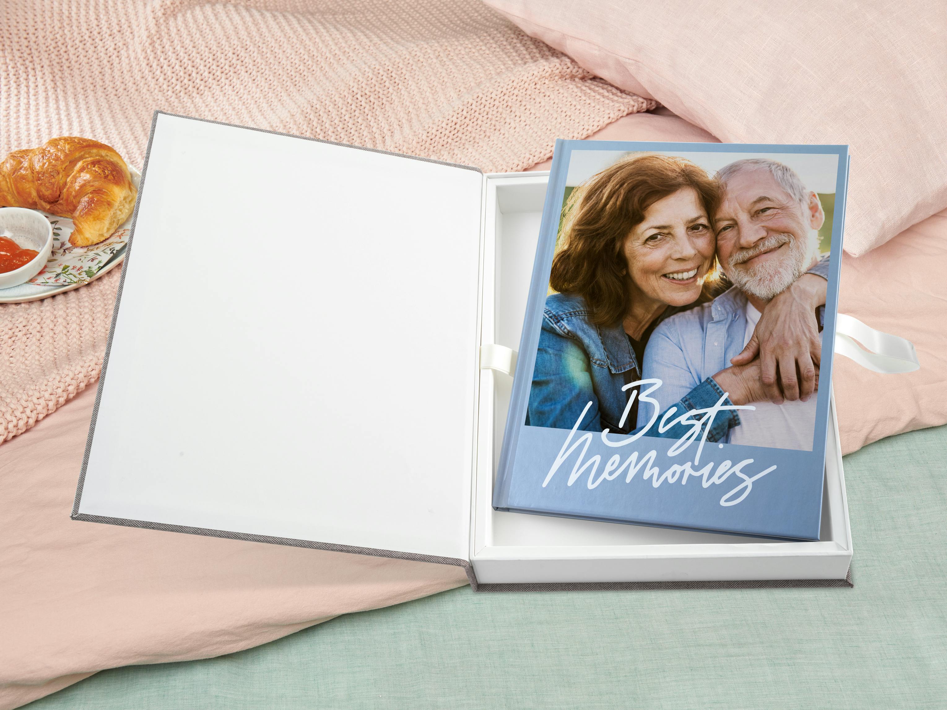 Livre photo Pixum avec photos d'un couple âgé, emballé dans un coffret cadeau en lin gris