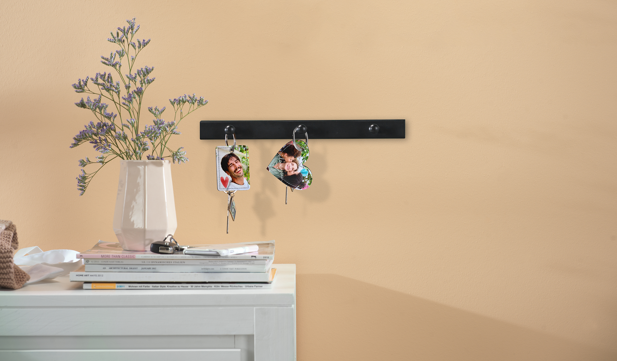 Een rechthoekige en hartvormige sleutelhanger met foto hangen aan een sleutelrek.