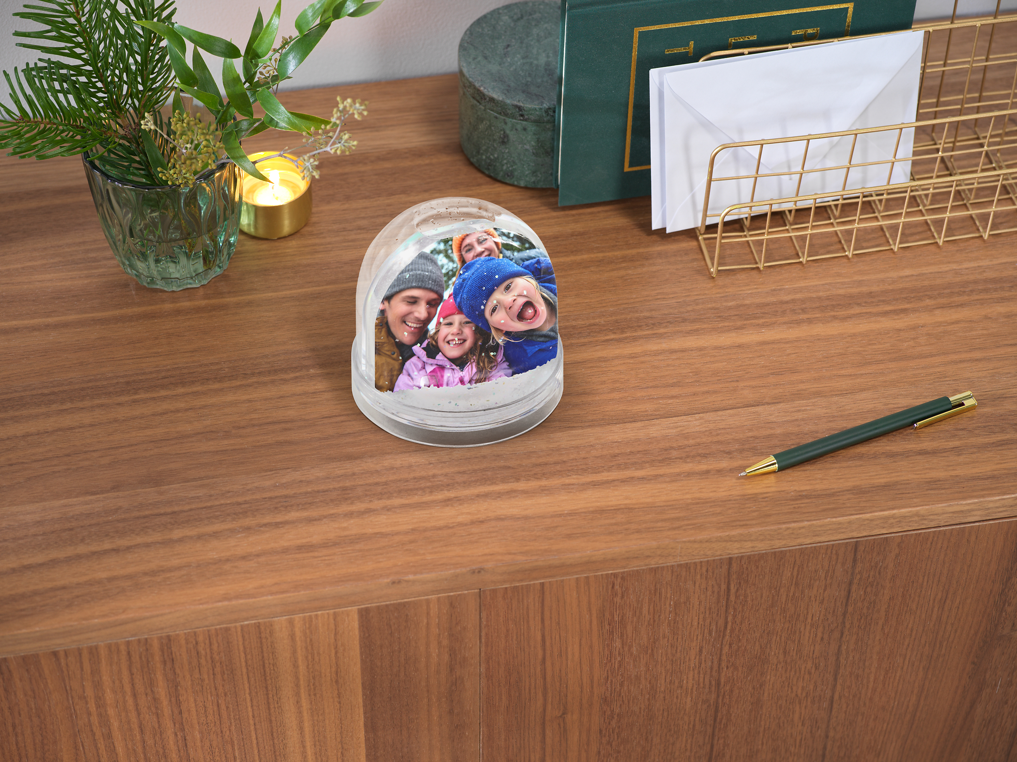 Glitzerkugel mit Schnee und einem winterlichen Bild von einer vierköpfigen Familie im Schnee