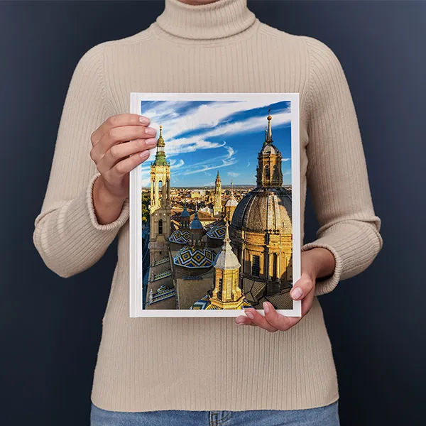 Una donna regge un Fotolibro Pixum grande verticale