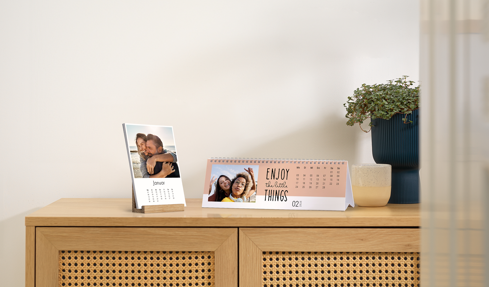Hay dos calendarios de mesa con fotos sobre una cómoda. Uno de los dos calendarios de mesa tiene la frase «Enjoy the little things» (Disfruta de las pequeñas cosas). Un calendario de mesa muestra la foto de una pareja, el otro, la foto de dos amigas.