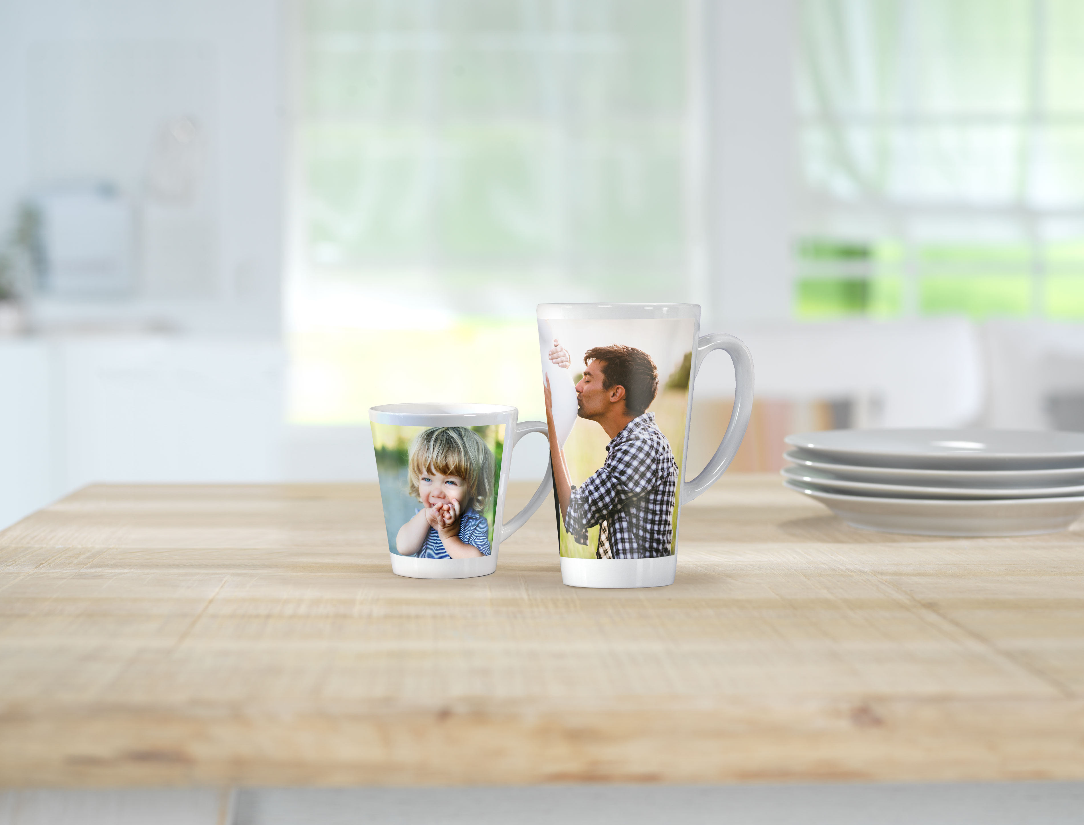 Twee bedrukte koffiemokken met familiefoto's staan op een houten tafel.