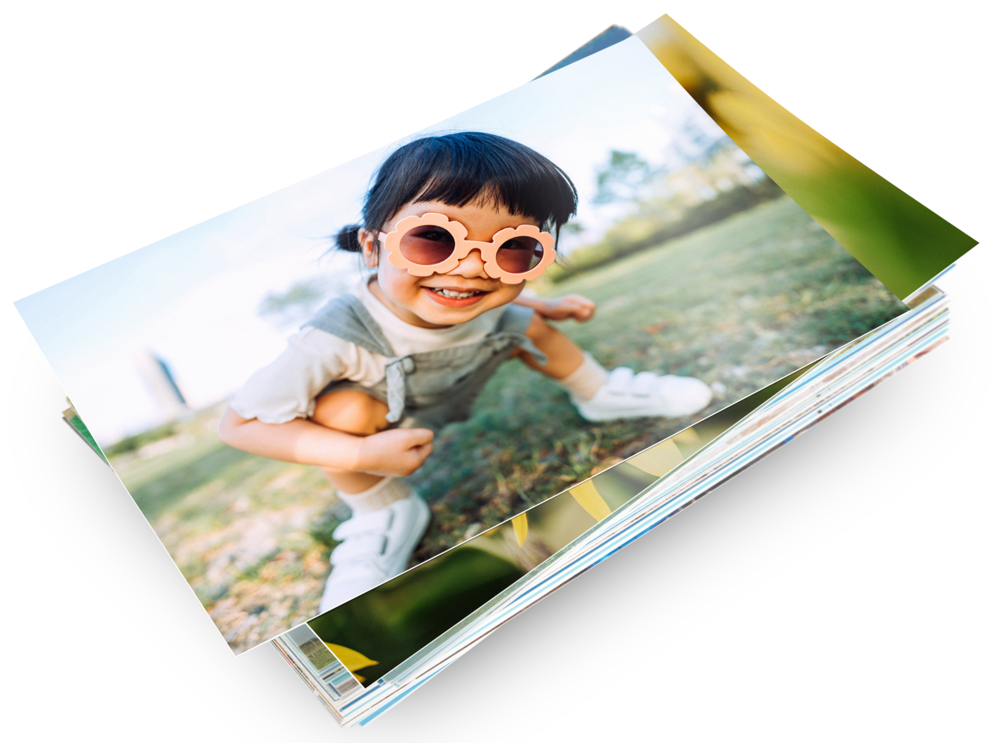 Ein Stapel mit Pixum Fotoabzügen und einem Kinderfoto auf dem ersten Abzug
