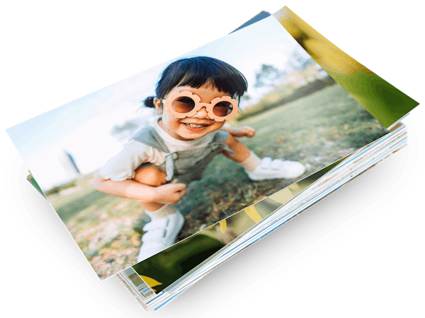 Ein Stapel mit Pixum Fotoabzügen und einem Kinderfoto auf dem ersten Abzug