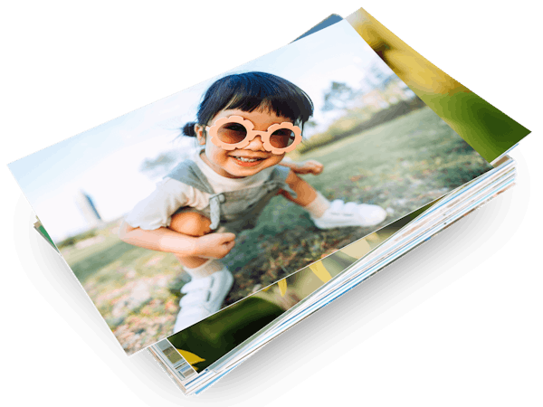 En stak Pixum-fotoprint og et barns foto på det første print