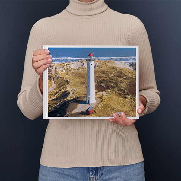 En kvinde holder en stor fotobog i tværformat med et stort landskab i sine hænder