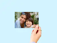 Fotoafdruk 10 cm Hand die een fotoafdruk van 10 cm met daarop een familie vasthoudt voor een neutrale achtergrond